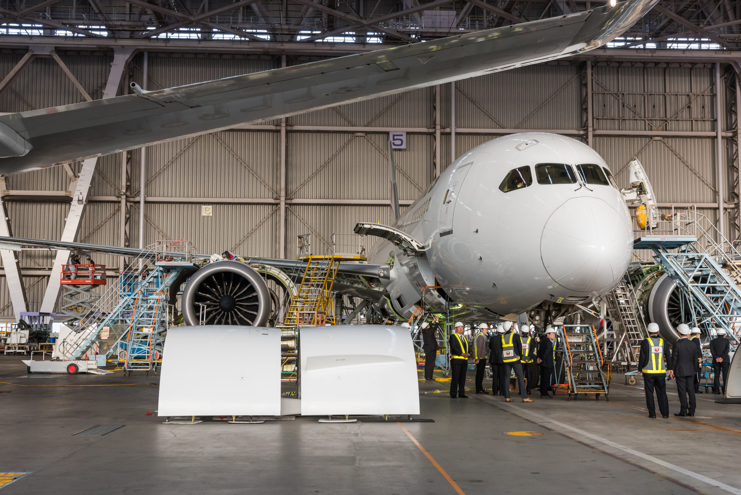 Workers gather around a plane in an airframe manufacturing plant