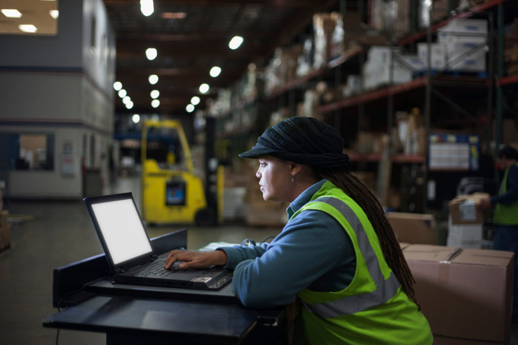 A female warehouse worker studies a computer screen