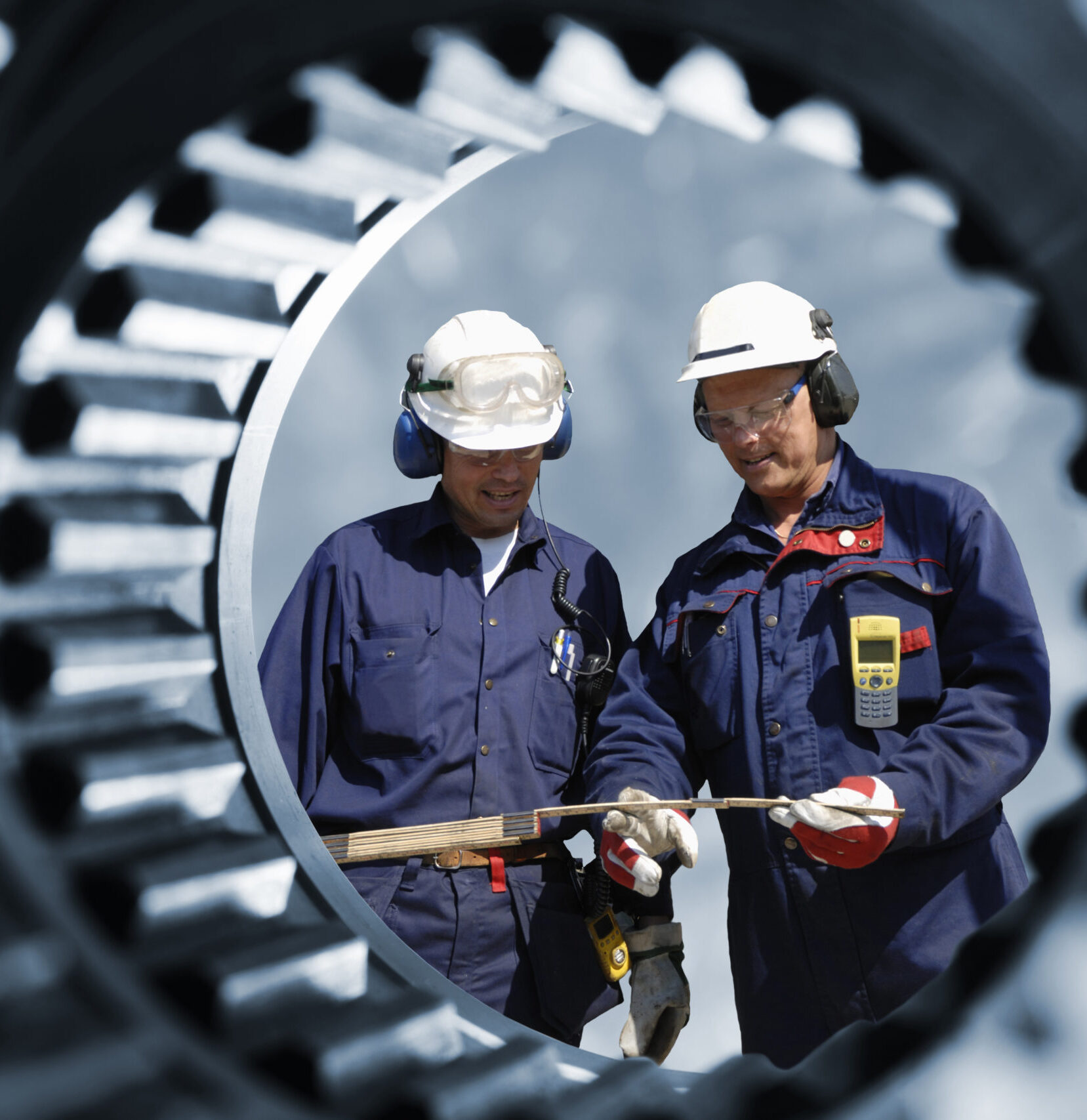 Two men in jumpsuits and hardhats seen through aperture