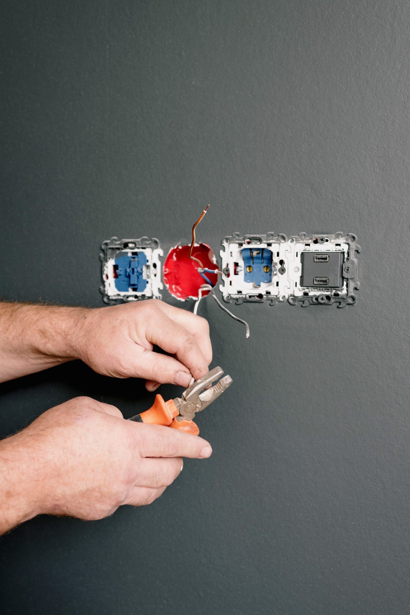 An electrician fixes a wall outlet.
