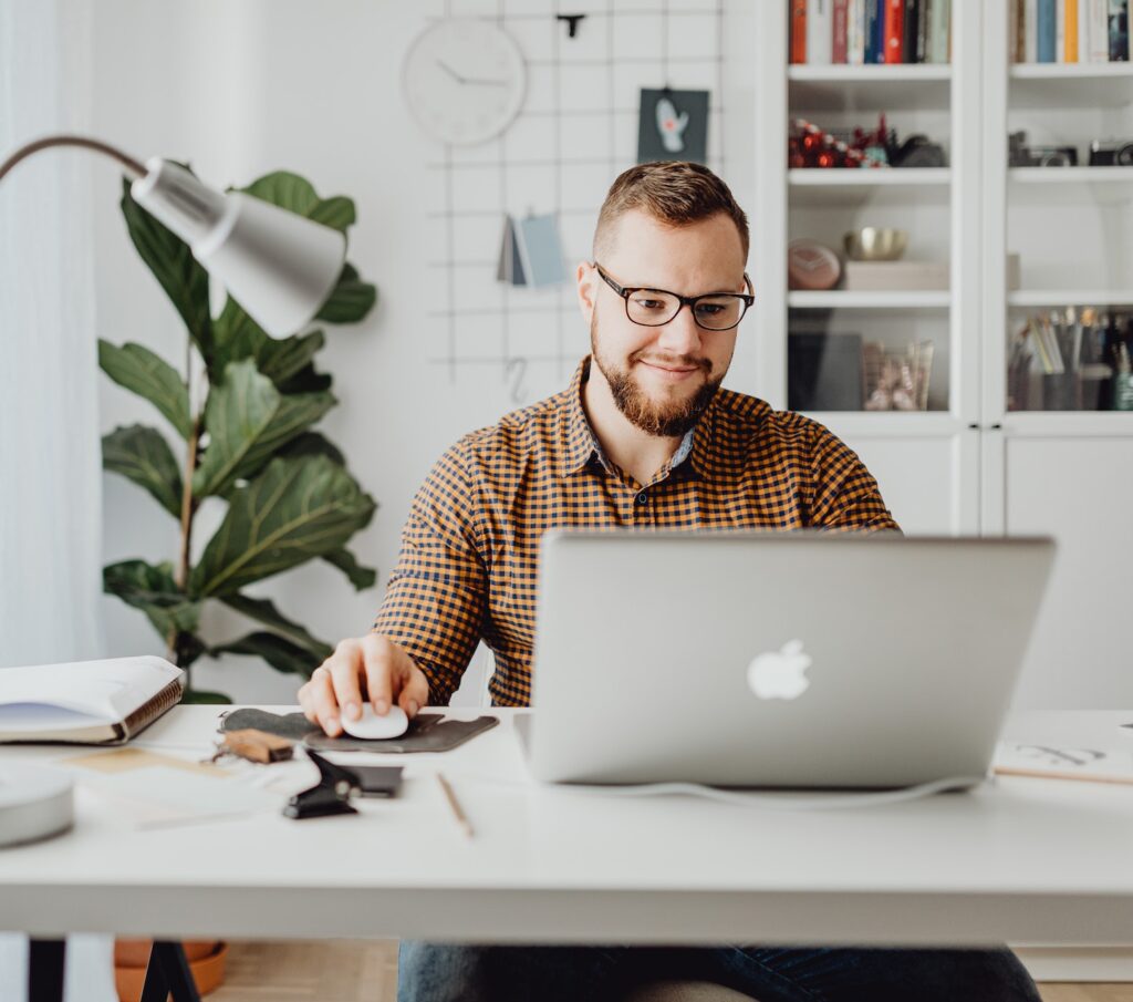 A man with glasses working on a laptop at a desk