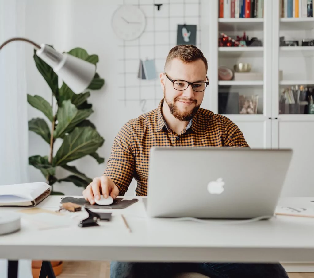 A man with glasses working on a laptop at a desk