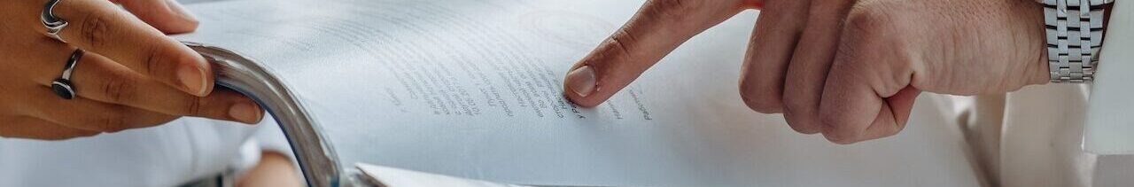 Close up of a man's hands pointing out something in a manual to a woman